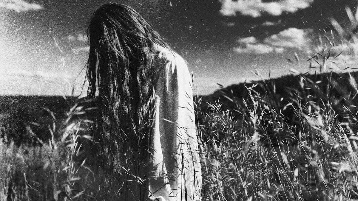 Long-haired person standing in a black and white field.