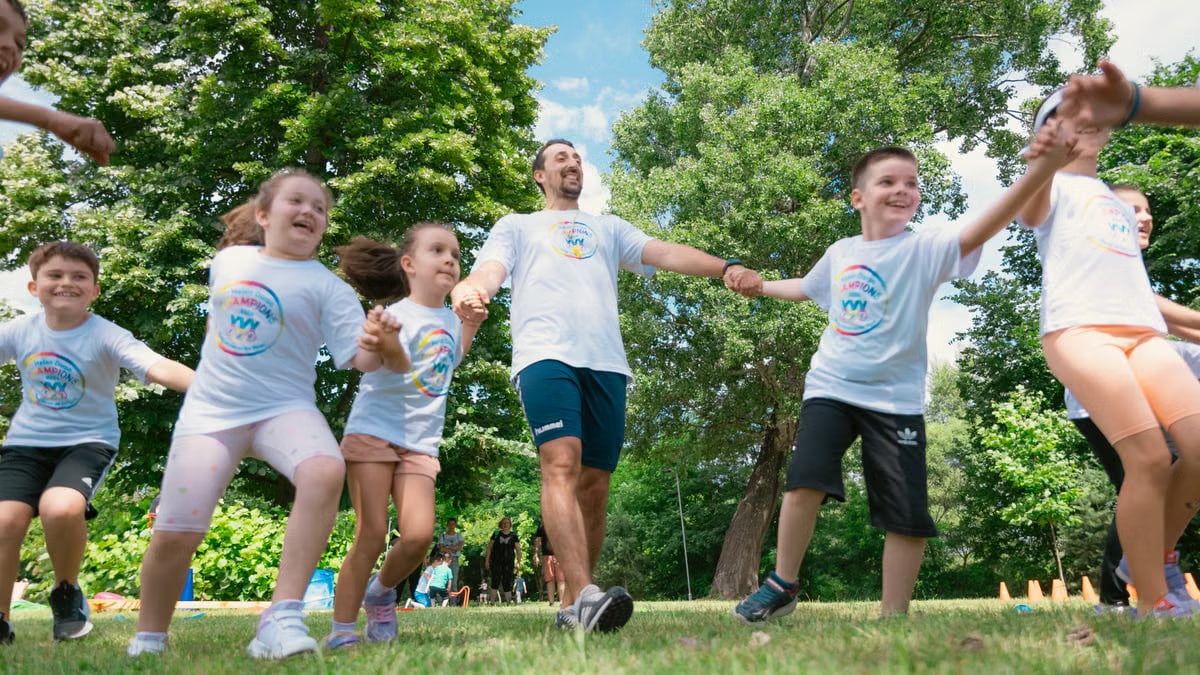 Group of joyful children playing outdoors with an instructor in a sunny park.